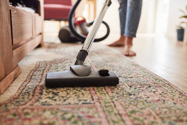 vacuuming red carpet with vacuum cleaner 